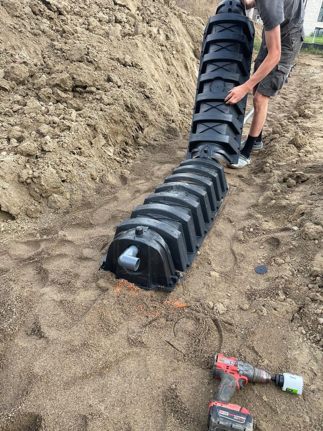 Installer placing plastic leaching chambers in a sand trench during a septic build