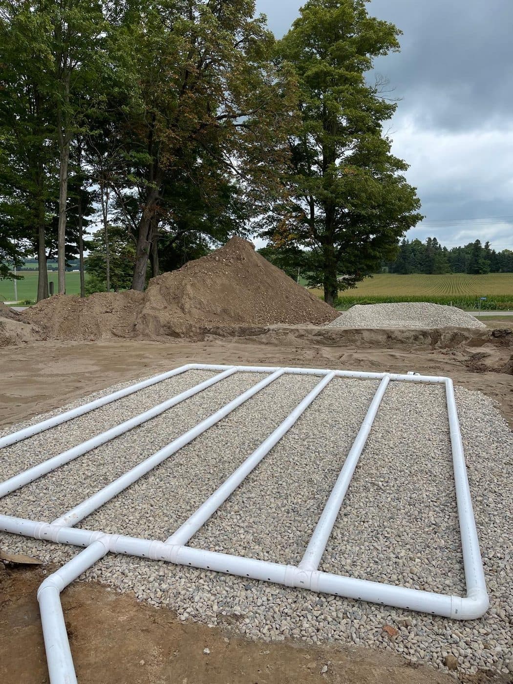 Completed septic distribution bed with PVC laterals laid on clear stone at a rural Ontario property