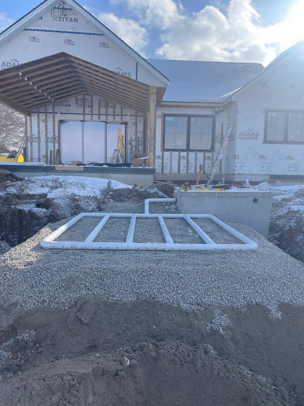 Septic distribution bed on stone in front of a new home under construction on a clear winter day